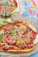 Healthy pizza with thin dough, ham and tomatoes