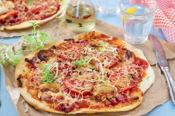 Healthy pizza with thin dough, ham and tomatoes