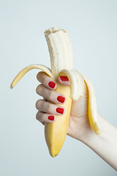 female hand holding a peeled biten banana