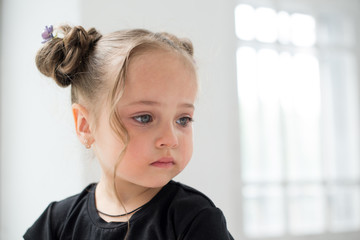 Beautiful sad little girl crying, on background white window