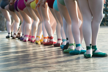 Obraz premium Ballerinas feet dancing on ballet shoes with several colors on stage during a performance.