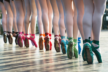 Ballerinas feet dancing on ballet shoes with several colors on stage during a performance. - obrazy, fototapety, plakaty