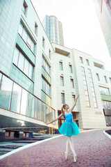 Ballet dancer dancing on street. Young ballerina in blue tutus full length