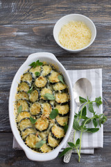 Gratin zucchini with cheese and greens on a wooden background. Delicious homemade food