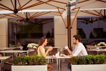 Happy married couple is on a honey moon, having brunch in nice cafe with modern interior, light summer terrace with green nice plants © deagreez