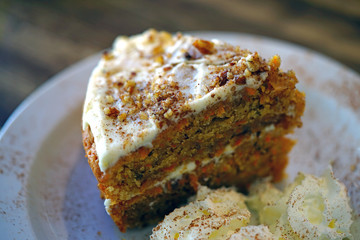 A slice of carrot cake on a plate with creamed frosting