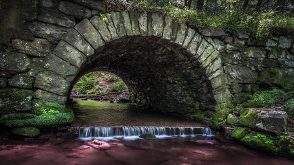 A stone culvert with stream passing under a road through Stokes State Forest, New Jersey
