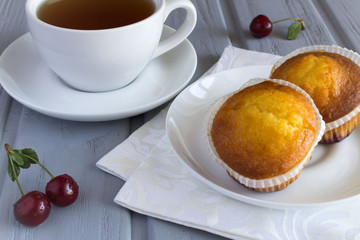 Cherry muffins and tea on the grey wooden background