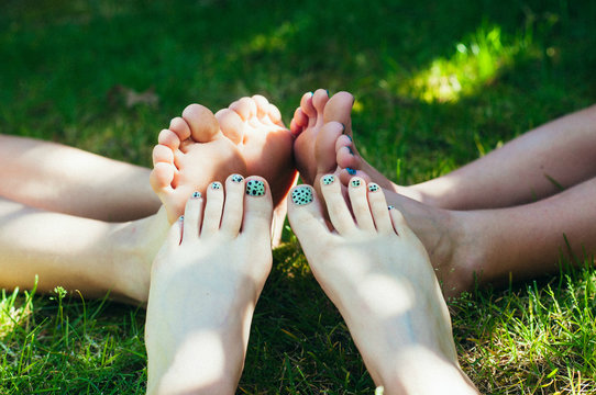 Three young girls with their feet together in the grass