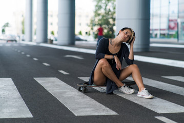 Young caucasian hipster woman with a longboard skateboard on the street