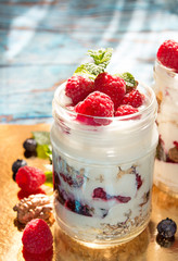 Healthy breakfast - dessert with yogurt, granola, outs flakes, jam, raspberries, blueberries, hazelnut and mint
