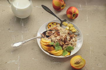 Breakfast from oatmeal porridge nectarine and milk cutlery