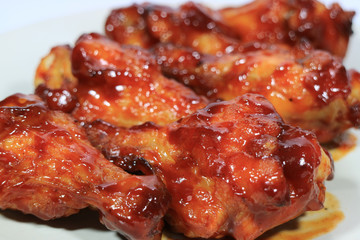 Closed up grilled chicken wing sticks served on white plate with selective focus 