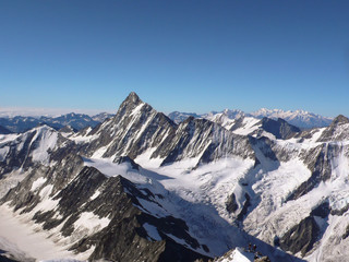two male climbers on a small peak in the foreground with a spectacular view of the Swiss Alps near Grindelwald with the Finsteraarhorn in the center