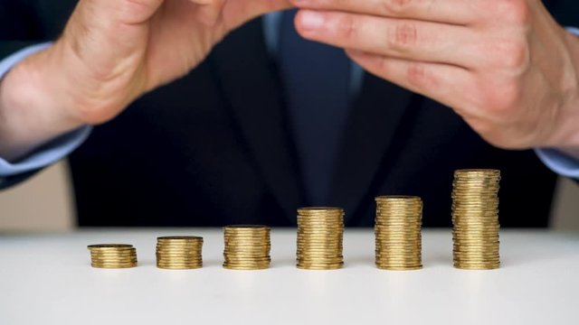 Man stacking gold coins into increasing columns