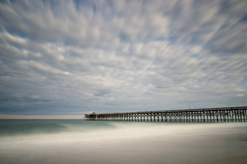 very long wooden pier leading out into the Atlantic Ocean with a sandy beach in the foreground in the summer in South Carolina