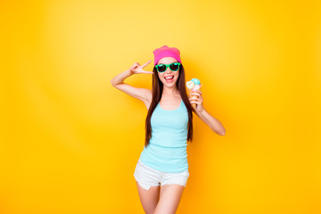 Asian funky hipster is posing for photo, wearing tourist`s outfit, glasses, hat, holds ice cream, so slim, attractive and  imposing!