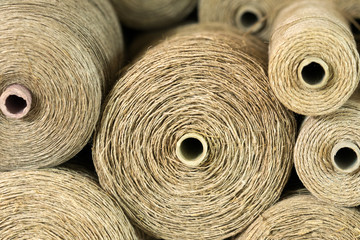 rolls and spools of brown thread on a shelf in a weaving studio