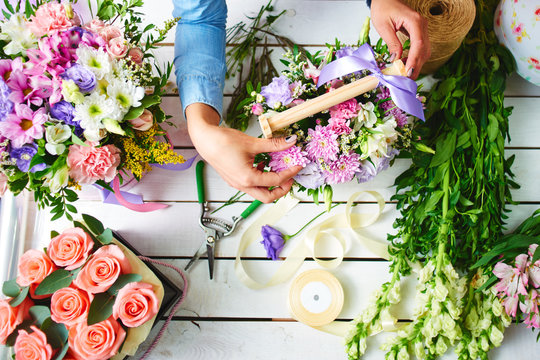 The hands of the florist close-up makes the bouquet on the white Board