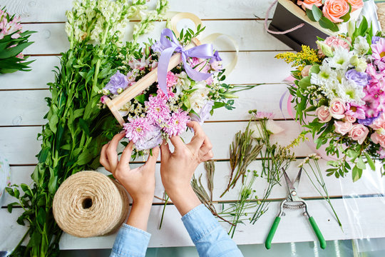 The hands of the florist close-up makes the bouquet on the white Board