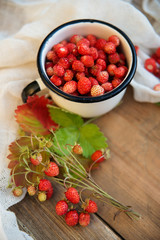 fresh wild strawberries in a Cup in the shape of a heart, symbol of love. Wooden background. The view from the top