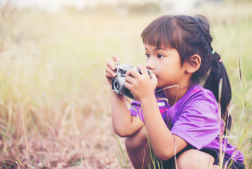 Woman with camera hiding behind the tree