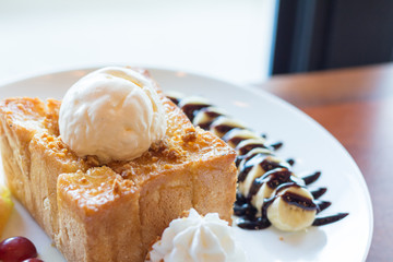 Honey toast with vanilla ice cream, whipped cream and chocolate syrup. Served with banana, grape and apple(selective focus)