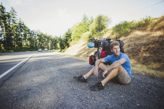 Young, fit man resting from bicycle touring expedition at sunrise