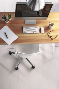 Overhead of a cool wooden desk with computer and some decorative cactus.