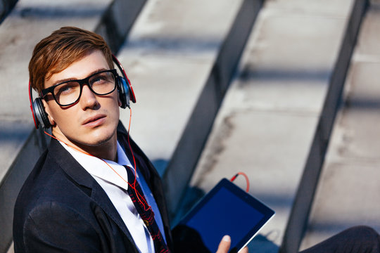 Fashionable Businessman Listening the Music With Headphones Through His Digital Tablet