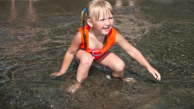 Little girl blonde 3 years Sitting on the beach and enjoying the wave. Slow motion. 4K