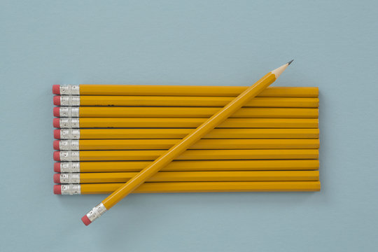 A sharpened yellow lead pencil lying on unsharpened pencils