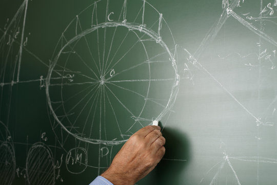 Close up of a mature professor writing and drawing on the blackboard