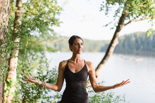 Beautiful woman practicing yoga by a lake