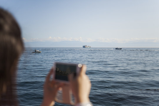 Woman taking ocean pictures with her smartphone