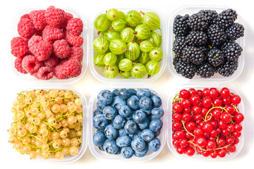 Collage of different fruits and berries isolated on white. Blueberries, cherries, blackberries, grapes, strawberries, currants. Collection of fruits and berries in a bowl. Top view