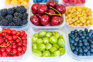Collage of different fruits and berries isolated on white. Blueberries, cherries, blackberries, grapes, strawberries, currants. Collection of fruits and berries in a bowl. Top view