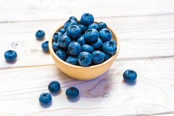 Blueberries in a wooden bowl. Top view. Ripe and tasty blueberries on a wooden background