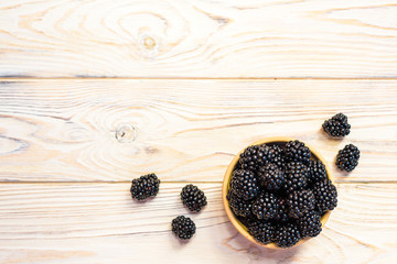 Fototapeta na wymiar Close up of ripe blackberries in a white ceramic bowl over rustic wooden background