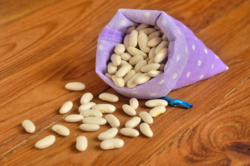Fototapeta na wymiar Beans are scattered on the wooden surface of a small fabric bag