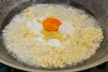 Instant noodles with egg are boiled in a pot