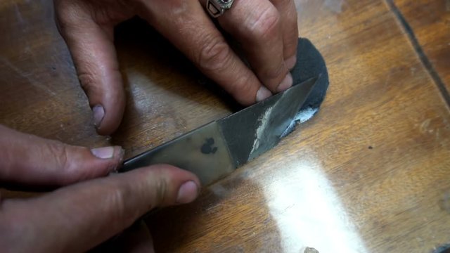 a shoemaker cleans a special knife black leather patch.