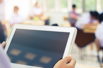 blurred of student testing in exercise, exams answer on a tablet computer in elementary, high school lesson in class room for test exams online education by finger clicking.