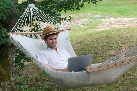 Homme et ordinateur portable dans un hamac