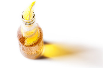 Bottle of blonde beer with lemon inside and white background
