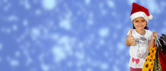 Little girl in fur-cap with shopping bags on blue background. Christmas