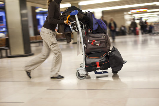 femme qui pousse un chariot de bagages en courant à l'aéroport