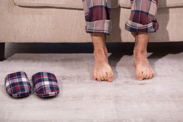 Close up view on mans legs on the carpet. Legs in pyjamas and slippers on the carpet, home atmosphere.