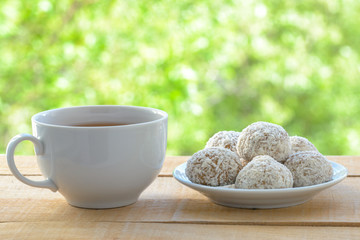 White mug with tea and gingerbread cookies on wooden table by the open window.