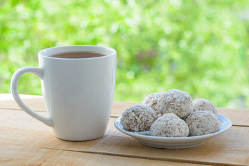 White mug with tea and gingerbread cookies on wooden table by the open window.